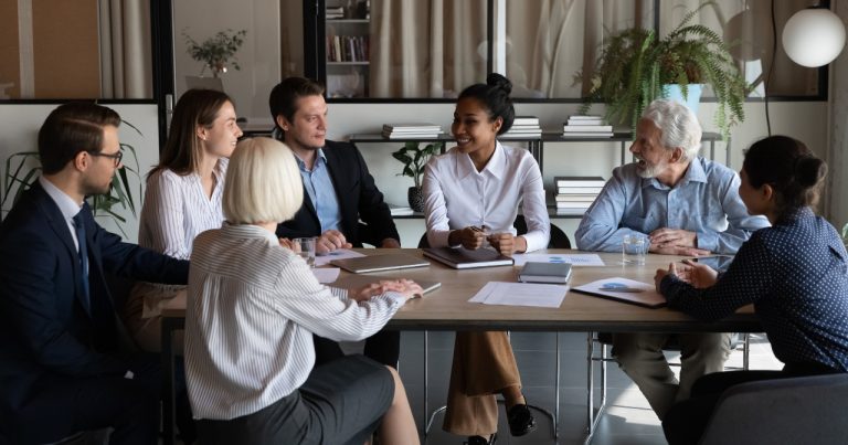 A group of board members meet around a table.